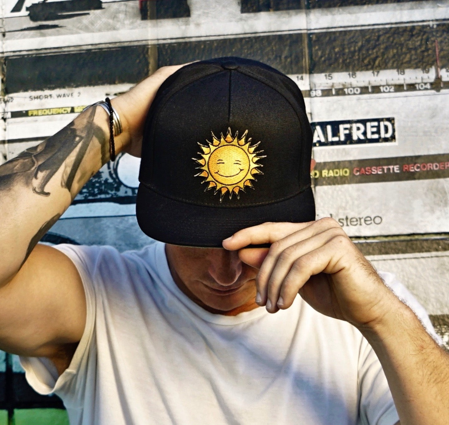 Man facing forward looking down showing the new black Kine Threads OG Twill Snapback Hat