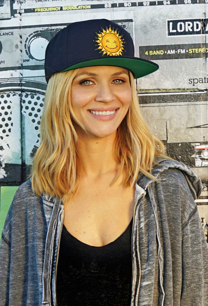 Woman facing forward smiling wearing a new blue Kine Threads OG Twill Snapback Hat